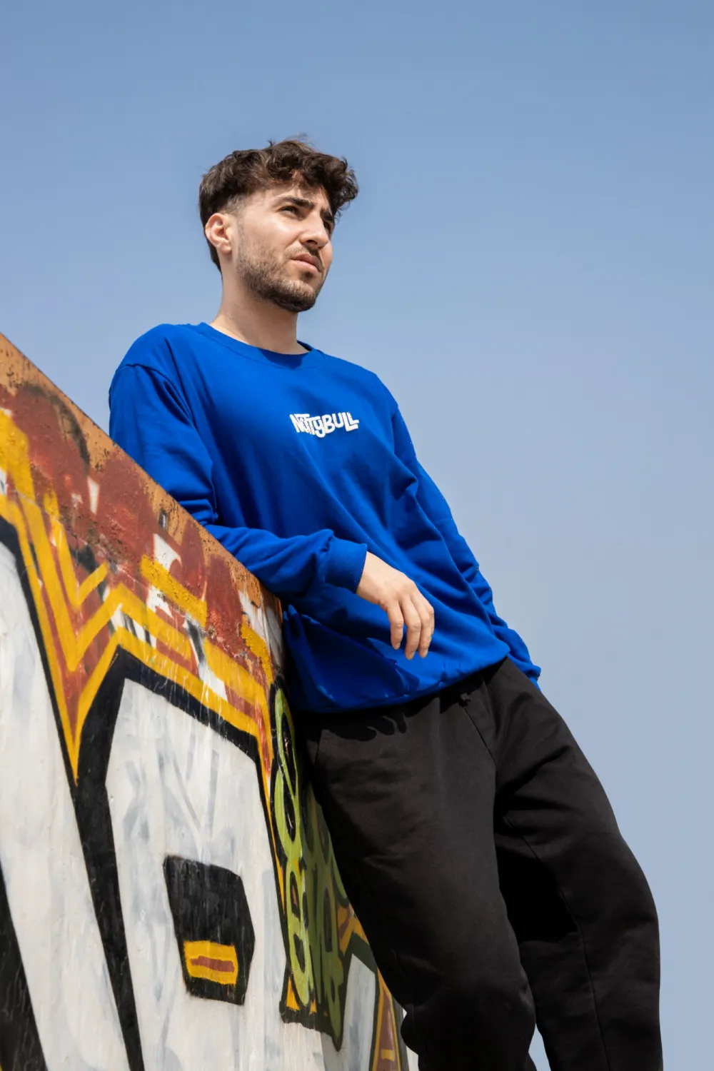 Model leaning on a graffiti wall in the royal blue sweatshirt